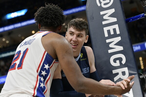 Philadelphia 76ers center Joel Embiid (21) and Memphis Grizzlies forward Jake LaRavia connect after a play in the second half of an NBA basketball game Wednesday, Nov. 20, 2024, in Memphis, Tenn. (AP Photo/Brandon Dill)