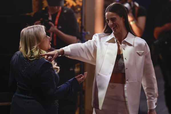 CORRECTS TO CAITLIN CLARK NOT CAITLYN CLARK - Iowa's Caitlin Clark, right, reacts after being selected first overall by the Indiana Fever during the first round of the WNBA basketball draft, Monday, April 15, 2024, in New York. (AP Photo/Adam Hunger)