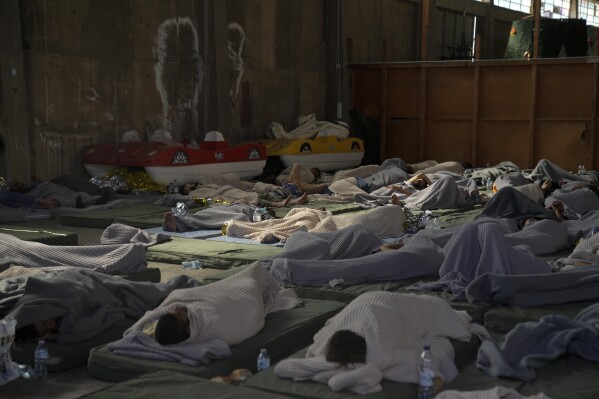 FILE - Survivors of a shipwreck sleep in a warehouse at the port in Kalamata town, about 240 kilometers (150 miles) southwest of Athens, Greece on June 14, 2023. The international rights groups Amnesty International and Human Rights Watch allege on Thursday, Dec. 14, 2023, that Greek authorities have failed to properly investigate allegations by some survivors that the rescue mission had been mishandled. (AP Photo/Thanassis Stavrakis, File)