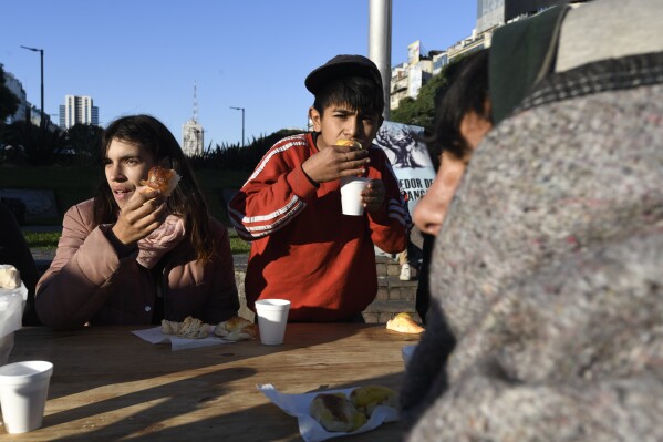 People eat a free breakfast served by a soup kitchen that was set up at the Obelisk as a protest against the city government's hygiene and cleanliness policy in Buenos Aires, Argentina, Tuesday, May 14, 2024. The policy involves authorities removing the homeless from the streets. (AP Photo/Gustavo Garello)