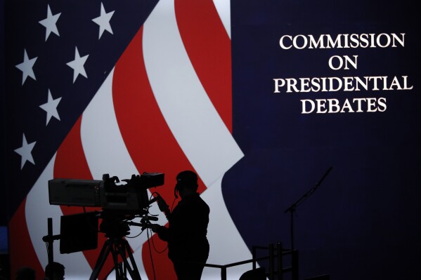 FILE - A cameraman is silhouetted against an an American flag during preparations for the presidential debate at Hofstra University in Hempstead, N.Y., Sept. 25, 2016. The nonpartisan Commission on Presidential Debates, which has planned presidential faceoffs in every election since 1988, has an uncertain future after President Joe Biden and former President Donald Trump struck an agreement to meet on their own. (Ǻ Photo/Mary Altaffer, File)