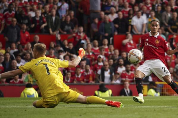 Manchester United's Antony, right, scores his side's opening goal past Arsenal's goalkeeper Aaron Ramsdale during the English Premier League soccer match between Manchester United and Arsenal at Old Trafford stadium, in Manchester, England, Sunday, Sept. 4, 2022. (AP Photo/Dave Thompson)