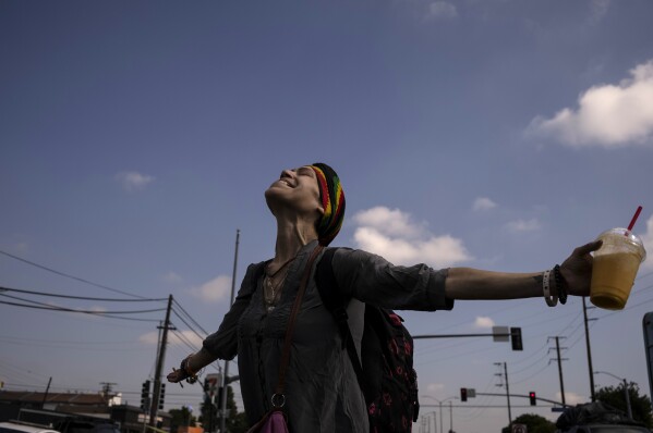 Noelia Nunez twirls in excitement while waiting to board a bus to a nearby motel, following the cleanup of her homeless encampment by city workers as part of Los Angeles Mayor Karen Bass' Inside Safe initiative in Los Angeles Tuesday, Oct. 24, 2023. "Today is a special day," said Nunez. (AP Photo/Jae C. Hong)