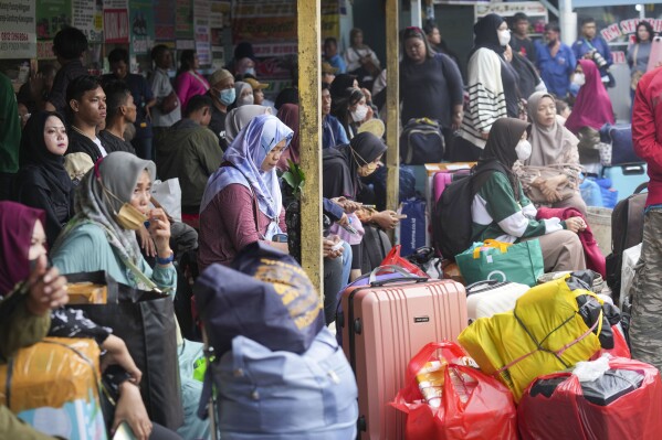 People wait for a bus to take them back home towns ahead of the Eid al-Fitr holiday at Pondok Pinang Bus Terminal in Jakarta, Indonesia, Thursday, March 27, 2025. (AP Photo/Tatan Syuflana)