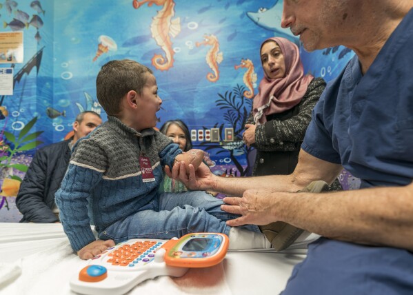 Four-year-old Omar Abu Kuwaik cries as orthopedic surgeon Dr. Scott Kozin examines his arm at Shriners Children's Hospital, Thursday, Jan. 18, 2024, in Philadelphia. (AP Photo/Peter K. Afriyie)