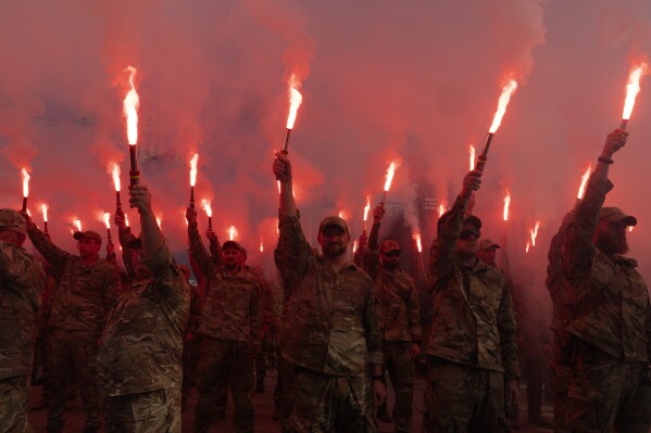 Soldiers of Ukraine's Azov battalion light flares at a rally demanding the release of Ukrainian prisoners of war who are held in captivity in Russia, at Independence Square in Kyiv, Ukraine, Sunday, July 28, 2024. (AP Photo/Efrem Lukatsky)