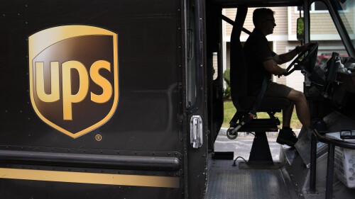 FILE - United Parcel Service driver Hudson de Almeida steers through a neighborhood while delivering packages, Friday, June 30, 2023, in Haverhill, Mass. UPS has reached a contract agreement with its 340,000-person strong union Tuesday, July 25, averting a strike that had the potential to disrupt logistics nationwide for businesses and households alike. (AP Photo/Charles Krupa, File)