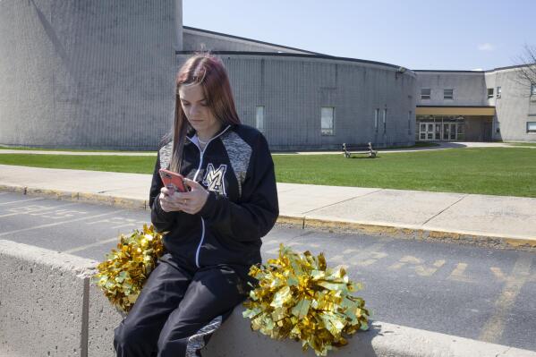 FILE - In this April 4, 2021, file photo provided by the American Civil Liberties Union, Brandi Levy wears her cheerleading outfit as she looks at her mobile phone outside Mahanoy Area High School in Mahanoy City, Pa. The Supreme Court ruled Wednesday, June 23, 2021, that the public school wrongly suspended Levy from cheerleading over a vulgar social media post she made after she didn't qualify for the varsity team. (Danna Singer/ACLU via AP, File)
