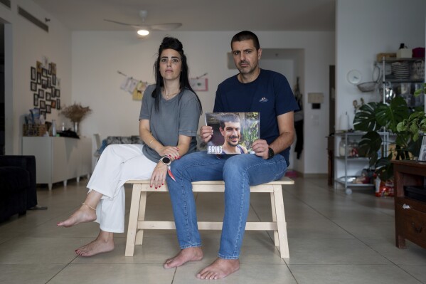 Hila Levy, sitting beside her husband Michael, holds up a portrait of his brother, 33-year-old Or Levy, in the family house in Ganei Tikva, Israel, Sunday, Oct. 29, 2023. Levy, an Israeli citizen, was abducted by Hamas militants from the 