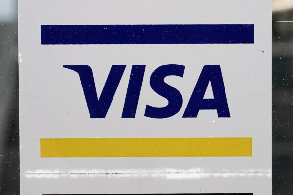 FILE - A Visa sign is displayed on the front door of a local business, April 27, 2021, in Urbandale, Iowa. Visa has announced major changes to how its credit and debit cards will operate in the U.S. Features in the works will lead to Americans to carry fewer physical cards in their wallets and make the 16-digit credit or debit card number printed on every physical card increasingly irrelevant. The new features unveiled Wednesday, May 15, 2024 will be some of the biggest changes to how payments operate since the U.S. rolled out chip-embedded cards several years ago. (AP Photo/Charlie Neibergall, file)