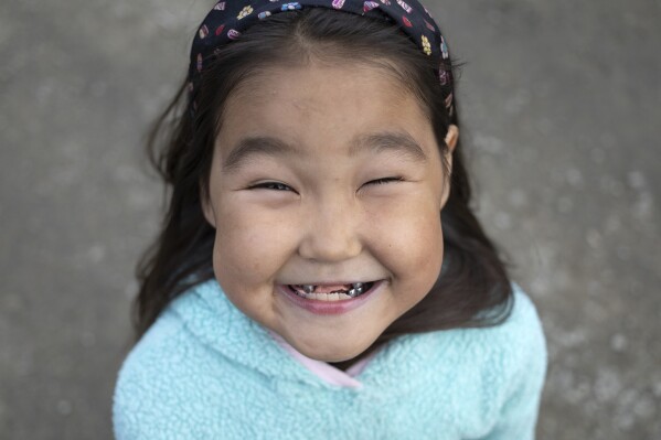 Tiffany Charles smiles for a photo while playing with friends at a local playground on Phillips Street, Friday, Aug. 18, 2023, in Akiachak, Alaska. (AP Photo/Tom Brenner)