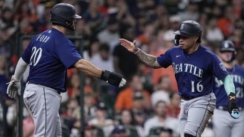 Seattle Mariners' Mike Ford (20) and Kolten Wong (16) celebrate after scoring on a single by Julio Rodriguez against the Houston Astros during the fourth inning of a baseball game Friday, July 7, 2023, in Houston. (AP Photo/Kevin M. Cox)