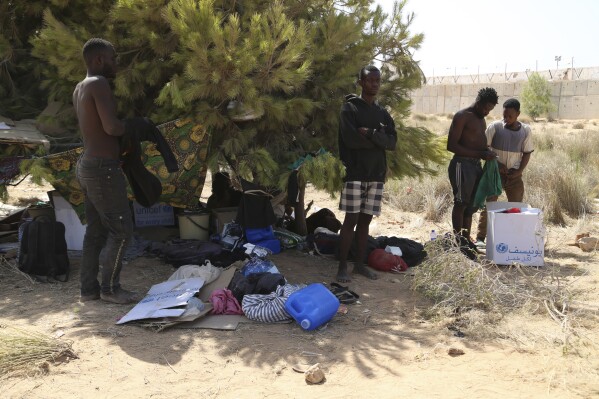 FILE - Migrants gather in a desert area on the Libyan side of the Tunisia-Libya border on Sunday July 23, 2023. Tunisia's interior minister insists that security forces don't dump sub-Saharan migrants in the desert border area with Libya and that migrants who make such claims, with some saying they were beaten by security forces, are 