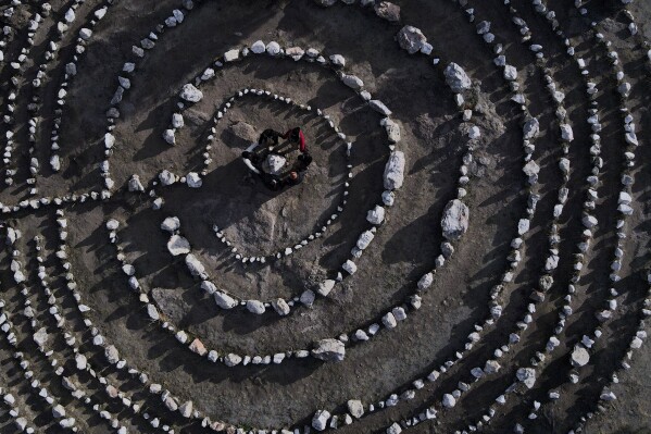 A group of Brazilian tourists hold hands standing in a circle at the heart of a stone labyrinth in the Pueblo Encanto spiritual theme park in Capilla del Monte, Argentina, Wednesday, July 19, 2023. In the pope's homeland of Argentina, Catholics have been renouncing the faith and joining the growing ranks of the religiously unaffiliated. Commonly known as the "nones," they describe themselves as atheists, agnostics, spiritual but not religious, or simply: "nothing in particular." (AP Photo/Natacha Pisarenko)