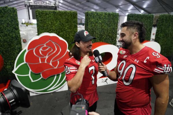 Utah quarterback Cameron Rising, left, is interview by teammate Devin Kaufusi during media day ahead of the Rose Bowl NCAA college football game against Penn State Saturday, Dec. 31, 2022, in Pasadena, Calif. (AP Photo/Marcio Jose Sanchez)
