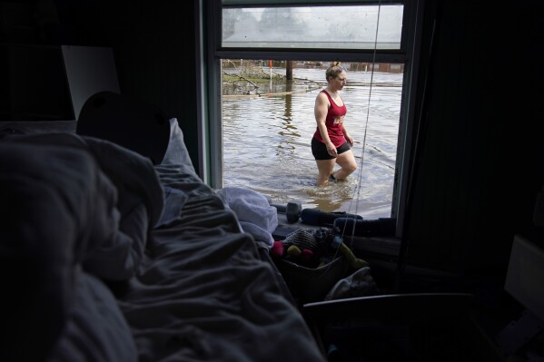 FILE - Emily Francois walks through floodwater beside her flood-damaged home in the aftermath of Hurricane Ida on Sept. 1, 2021, in Jean Lafitte, La. (AP Photo/John Locher, File)
