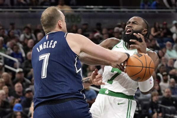 Boston Celtics' Jaylen Brown, right, is fouled by Orlando Magic's Joe Ingles as he goes up for a shot during the first half of an NBA basketball game, Friday, Nov. 24, 2023, in Orlando, Fla. (AP Photo/John Raoux)