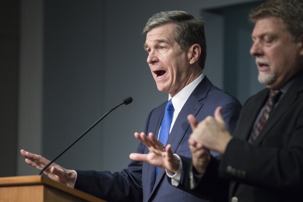 FILE - North Carolina Gov. Roy Cooper, left, answers questions at a news conference in which he declared a state of emergency for North Carolina, March 10, 2020. Cooper’s decisions during the COVID-19 pandemic that resulted in bars being shuttered or severely restricted while restaurants that served alcohol could reopen were "illogical" and don't appear justified by evidence, a state appeals court ruled Tuesday, April 16, 2024. (Julia Wall/The News & Observer via AP, File)