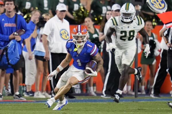 Florida wide receiver Ricky Pearsall (1) looks for running room after a reception as he is chased by Charlotte linebacker Demetrius Knight II (28) during the first half of an NCAA college football game, Saturday, Sept. 23, 2023, in Gainesville, Fla. (AP Photo/John Raoux)