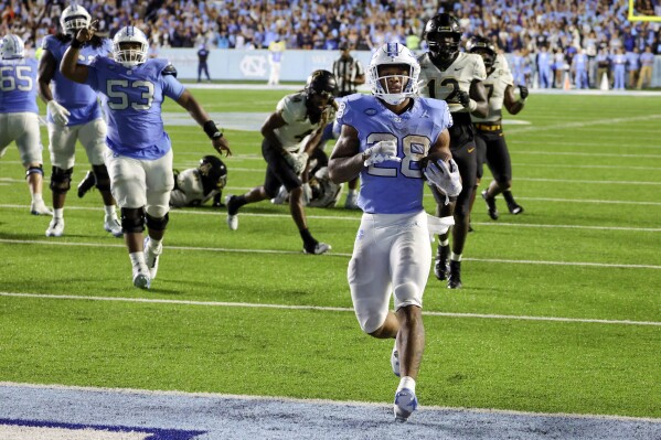 North Carolina running back Omarion Hampton (28) runs in for a touchdown with North Carolina offensive lineman Willie Lampkin (53) cheering him on during the second overtime of an NCAA college football game against Appalachian State, Saturday, Sept. 9, 2023, in Chapel Hill, N.C. (AP Photo/Reinhold Matay)