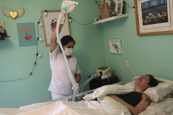FILE - A nurse readies a portable medical ventilator for Ana Estrada, a Peruvian psychologist, to receive oxygen in her bedroom, Lima, Peru, Dec. 18, 2019. Estrada, who suffered from an incurable disease and was authorized in 2022 by Peru's Supreme Court to receive euthanasia, has died, her lawyer said Monday, April 22, 2024. (AP Photo/Martin Mejia, File)