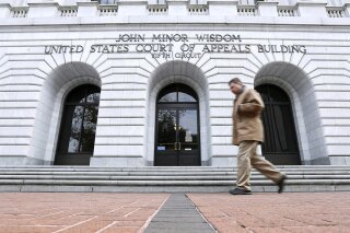 FILE - In this Jan. 7, 2015, file photo, a man walks in front of the 5th U.S. Circuit Court of Appeals in New Orleans. Texas should be allowed to halt a common second-trimester abortion procedure, the state's lawyers told a federal appeals court Thursday, Jan. 21, 2021, in a hearing punctuated by debates over fetal pain and the rights of women to medically safe abortion. (AP Photo/Jonathan Bachman, File)