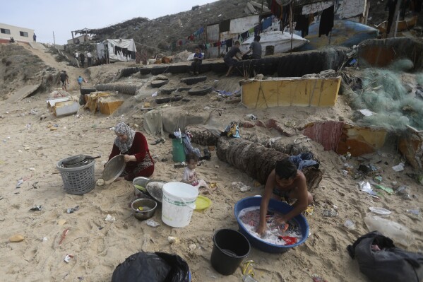 FILE - Palestinians resort to the sea water to bathe and clean their tools and clothes due the continuing water shortage in the Gaza Strip, on the beach of Deir al-Balah, Central Gaza Strip, Sunday, Oct. 29, 2023. With the Israel-Hamas war in its second month and more than 10,000 people killed in Gaza, trapped civilians are struggling to survive without electricity or running water. Each day has become a mind-numbing cycle of searching for bread and water and waiting in lines. A sense of desperation has strained Gaza's close-knit society. (AP Photo/Mohammed Dahman, File)