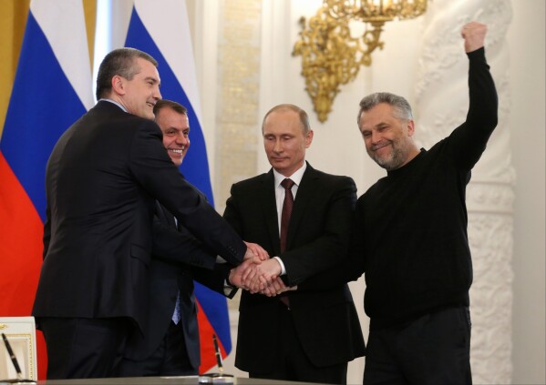 FILE - Russian President Vladimir Putin, second right, Speaker of the Crimean legislature Vladimir Konstantinov, second left, Crimean Premier Sergei Aksyonov, left, and Sevastopol Mayor Alexei Chalyi, right, shake hands after signing a treaty for Crimea to join Russia in the Kremlin in Moscow, Tuesday, March 18, 2014. Russia's quick and bloodless seizure of Ukraine's Crimean Peninsula, home to Russia's Black Sea fleet and a popular vacation site, touched off a wave of patriotism and sent Putin's popularity soaring. "Crimea is ours!" became a popular slogan in Russia. (Yekaterina Shtukina, Sputnik, Pool Sputnik Government via AP, File)