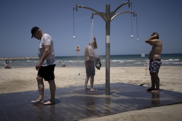 Men shower at a public beach as they take refuge from a summer heat wave in Tel Aviv, Israel on Thursday, July 13, 2023. (AP Photo/Maya Alleruzzo)