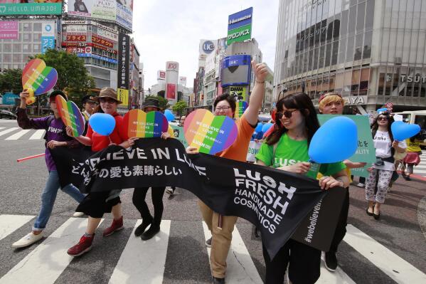 FILE - People march with rainbow-colored and heart-shaped posters and a banner during the Tokyo Rainbow Pride parade celebrating the lesbian, gay, bisexual, and transgender and queer or questioning (LGBTQ) community in Tokyo's Shibuya district, May 7, 2017. Japan's capital has announced Tuesday, May 10, 2022, it will start recognizing same-sex partnerships to ease the burdens faced by residents in their daily lives, but the unions will not be considered legal marriages. (AP Photo/Shizuo Kambayashi, File)
