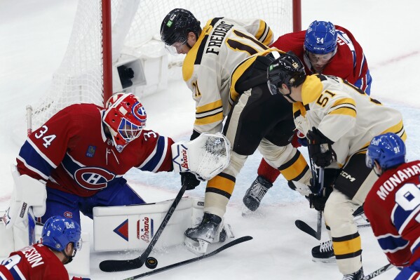 Boston Bruins' Trent Frederic (11) battles for control of the puck against Montreal Canadiens goaltender Jake Allen (34) during the second period of an NHL hockey game Saturday, Nov. 18, 2023, in Boston. (AP Photo/Michael Dwyer)