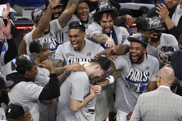Dallas Mavericks guard Luka Doncic, center, celebrates with teammates after Game 5 of the Western Conference finals in the NBA basketball playoffs against the Minnesota Timberwolves, Thursday, May 30, 2024, in Minneapolis. The Mavericks won 124-103, taking the series 4-1 and moving on to the NBA Finals. (AP Photo/Matt Krohn)