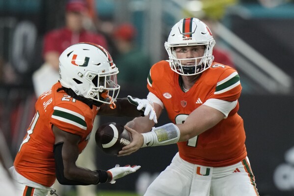 Miami quarterback Tyler Van Dyke (9) hands off to running back Henry Parrish Jr. (21) during the first half of an NCAA college football game against Miami (Ohio), Friday, Sept. 1, 2023, in Miami Gardens, Fla. (AP Photo/Wilfredo Lee)
