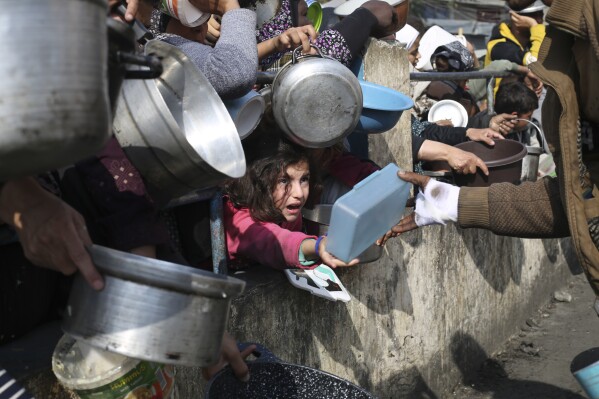 Palestinians line up for free food during the ongoing Israeli air and ground offensive on the Gaza Strip in Rafah, Tuesday, Jan. 9, 2024. (AP Photo/Hatem Ali)