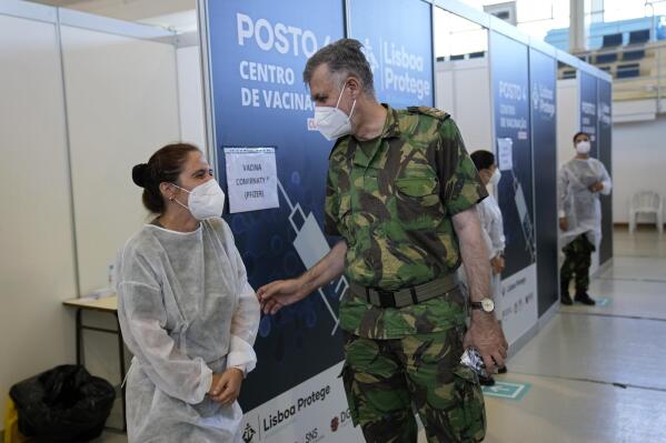 Rear Admiral Henrique Gouveia e Melo shares a joke with a military nurse during a visit to a vaccination center in Lisbon, Tuesday, Sept. 21, 2021. As Portugal nears its goal of fully vaccinating 85% of the population against COVID-19 in nine months, other countries want to know how it was able to accomplish the feat. A lot of the credit is going to Gouveia e Melo. (AP Photo/Armando Franca)