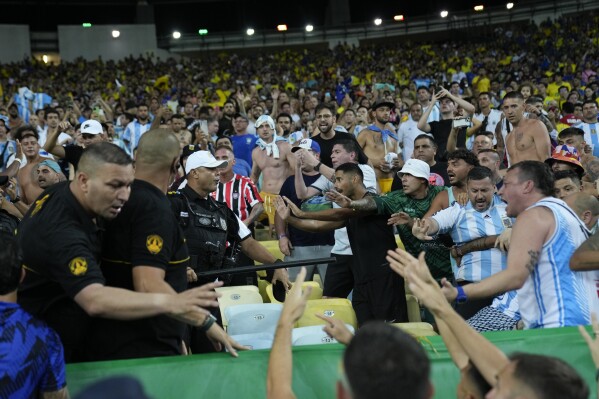 La policía intenta detener una pelea entre fanáticos brasileños y argentinos en las gradas antes de un partido de fútbol de clasificación para la Copa Mundial de la FIFA 2026 en el estadio Maracaná de Río de Janeiro, Brasil, el martes 21 de noviembre de 2023. (Foto AP/Silvia Izquierdo )