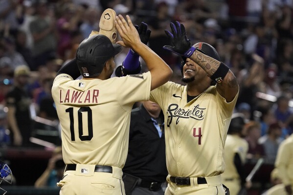 Arizona Diamondbacks' Ketel Marte (4) is greeted at home plate by Jordan Lawlar (10) after hitting a two-run home run against the Chicago Cubs during the sixth inning of a baseball game Sunday, Sept. 17, 2023, in Phoenix. (AP Photo/Darryl Webb)