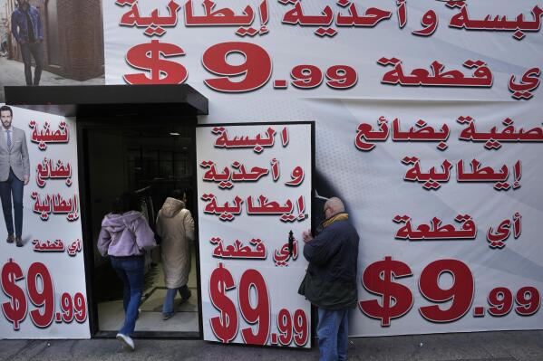 Store displays advertising in Arabic that reads "Italian clothes and shoes for 9.99 $" in Beirut, Lebanon, Wednesday, March 1, 2023. Lebanon started pricing consumer goods in U.S. dollars Wednesday as the value of the Lebanese pound hit new lows. (AP Photo/Hassan Ammar)