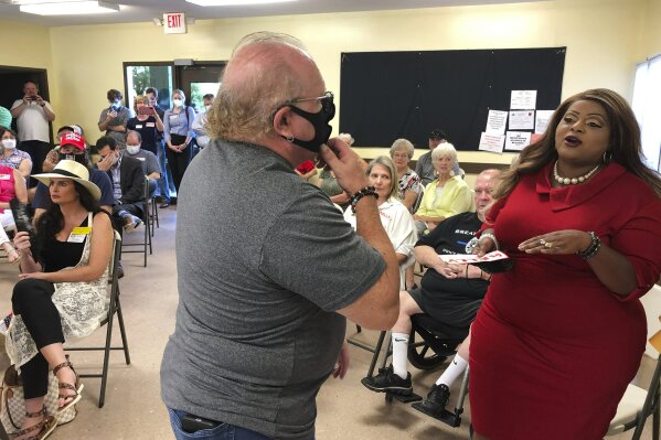 CORRECTS LAST NAME TO JAMES, NOT GAINES - Triana Arnold James is blocked by a man as she protests a speech by U.S. Sen. Kelly Loeffler, Thursday, Sept 3, 2020, in Cumming, Ga. James and a fellow activist kept Loeffler from finishing a campaign speech. (AP Photo/Jeff Amy)