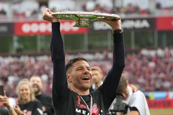 Leverkusen's head coach Xabi Alonso celebrates with the trophy as his team won the German Bundesliga, after the German Bundesliga soccer match between Bayer Leverkusen and FC Augsburg at the BayArena in Leverkusen, Germany, Saturday, May 18, 2024. Bayer Leverkusen have won the Bundesliga title for the first time. It is the first team in Bundesliga history, that won the championship unbeaten for the whole season. (AP Photo/Martin Meissner)