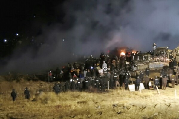 FILE - In this Nov. 20, 2016 file photo, provided by Morton County Sheriff's Department, law enforcement and protesters clash near the site of the Dakota Access pipeline on Sunday, Nov. 20, 2016, in Cannon Ball, N.D. A federal judge in North Dakota has dismissed the excessive-force lawsuit of a New York woman who was injured in an explosion during the protests of the Dakota Access oil pipeline. (Morton County Sheriff's Department via AP, File)