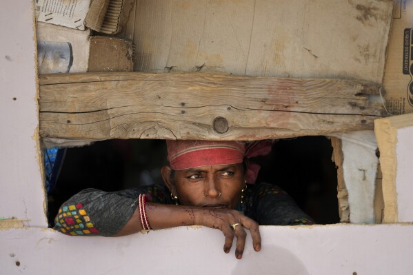 Waste picker Salmaa Shekh looks outside a temporary shelter during a heat wave at a garbage dump on the outskirts of Jammu, India, Thursday, June 20, 2024. Shekh and her family are among millions of people who scratch out a living searching through India's waste — and climate change is making a hazardous job more dangerous than ever. (AP Photo/Channi Anand)