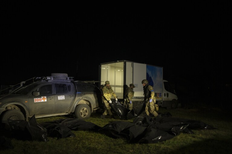 Team members of Oleksii Yukov offload the bodies of Russian soldiers they've collected from the frontline from their pickup truck in the Sloviansk region, Ukraine, Tuesday, Oct. 24, 2023. More than half a million people have been killed or seriously injured in two years of war in Ukraine, according to Western intelligence estimates -- a human toll not seen in Europe since World War II. The question of who prevails is being increasingly shaped by which side can tolerate higher losses. (AP Photo/Bram Janssen)