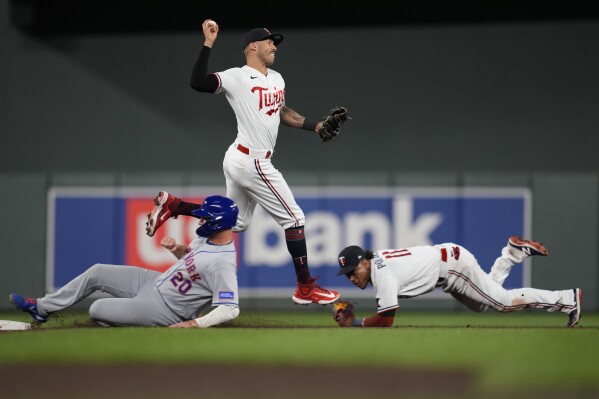 Minnesota Twins shortstop Carlos Correa throws to first base after forcing out New York Mets' Pete Alonso, left, during the ninth inning of a baseball game Friday, Sept. 8, 2023, in Minneapolis. Mark Vientos was safe at first. (AP Photo/Abbie Parr)