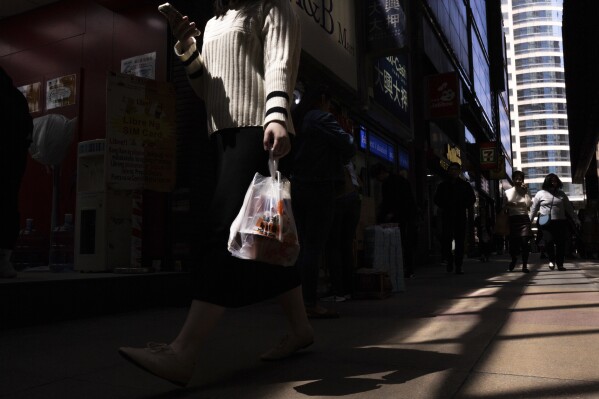 A pedestrian carries takeaway food plastic bag in Hong Kong, Wednesday, March 13, 2024. Hong Kong has long been a major producer and consumer of great food, and a great amount of plastic and Styrofoam to go with it. That’s going to change as new legislation aiming to stop the sale and distribution of Styrofoam products and single-use plastic cutlery went into effect on Monday, April 22, 2024.(AP Photo/Louise Delmotte)