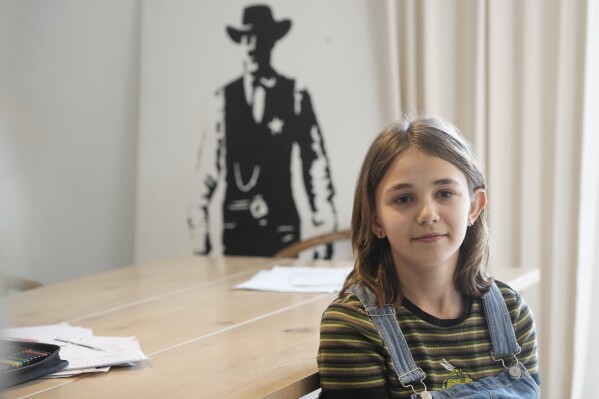 Ola Kozak, 11, sits at the table where she used to do her homework at the family home in Warsaw, Poland, Friday April 5, 2024. Ola is happy that Poland's government has ordered strict limits on the amount of homework that teachers can impose on the lower grades, starting in April. Julian enjoyed doing his homework. (AP Photo/Czarek Sokolowski)