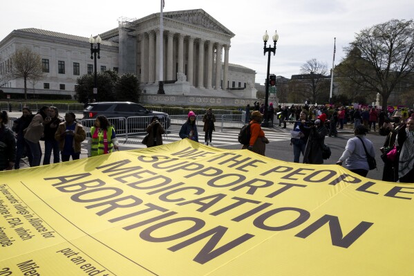 Abortion rights activists unfurl a banner, created by the ACLU, filled with names of people who said they support the continued access to medication abortion, outside the Supreme Court, Tuesday, March 26, 2024, in Washington. The Supreme Court is hearing arguments in its first abortion case since conservative justices overturned the constitutional right to an abortion two years ago. At stake in Tuesday's arguments is the ease of access to a medication used last year in nearly two-thirds of U.S. abortions. (AP Photo/Amanda Andrade-Rhoades)