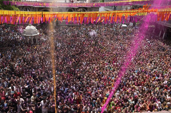 Devotees cheer as colored powder and water is sprayed on them during celebrations marking Holi at the Kalupur Swaminarayan temple in Ahmedabad, India, Sunday, March 24, 2024. (AP Photo/Ajit Solanki)