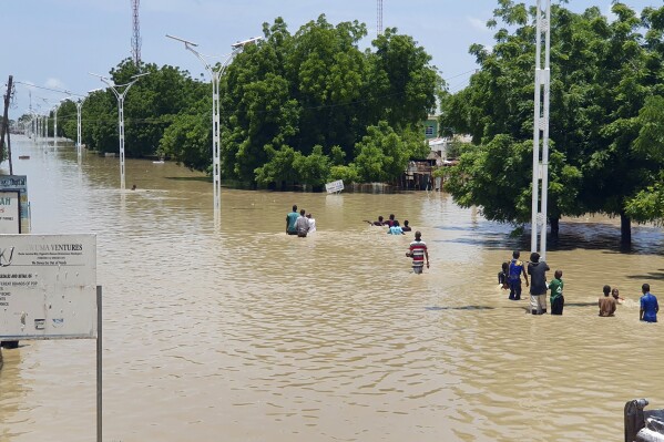 People walk through floodwaters following a dam collapse in Maiduguri, Nigeria Sept 10, 2024. (AP Photos/ Joshua Olatunji, File)