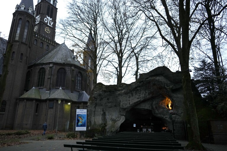 A man walks near a grotto at the church of Sint Willesbrord, Netherlands on Friday, Dec. 1, 2023. (AP Photo/Virginia Mayo)